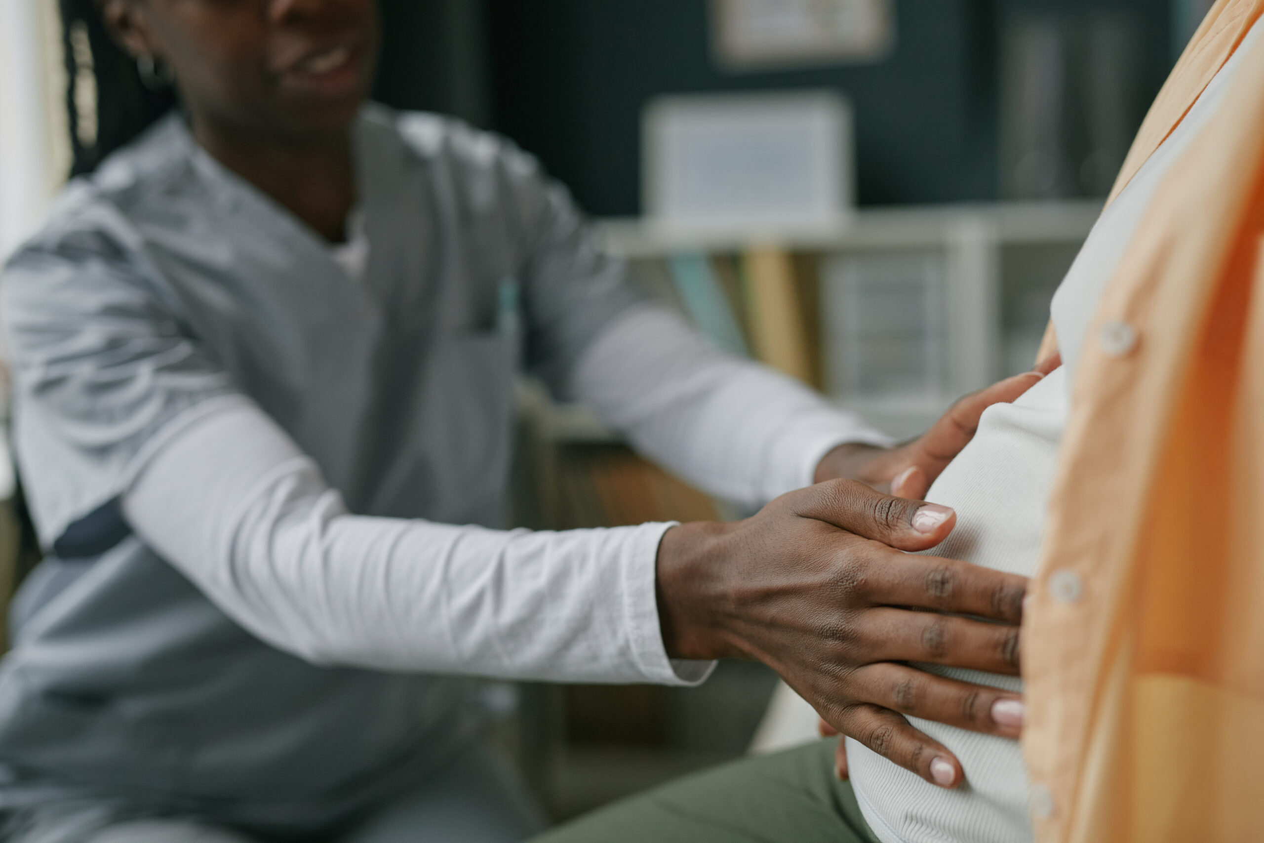 Young Adult Woman Receiving Prenatal Checkup from Black Female Doctor