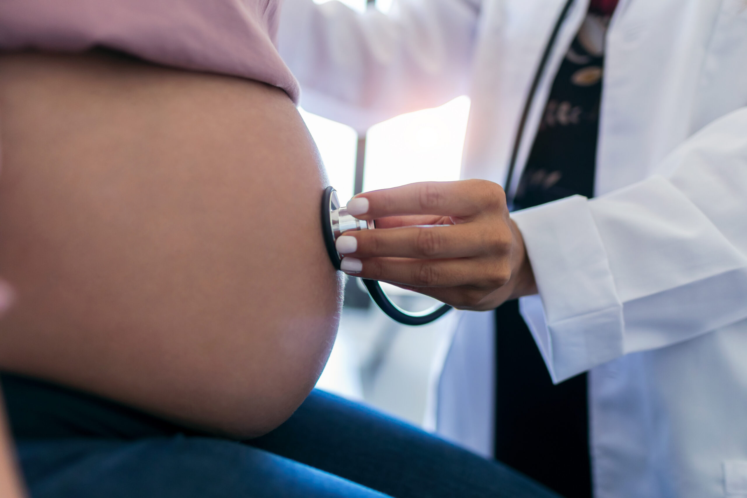 Close-up of woman gynecologist checking the heartbeat baby of her pregnant patient in the clinic.